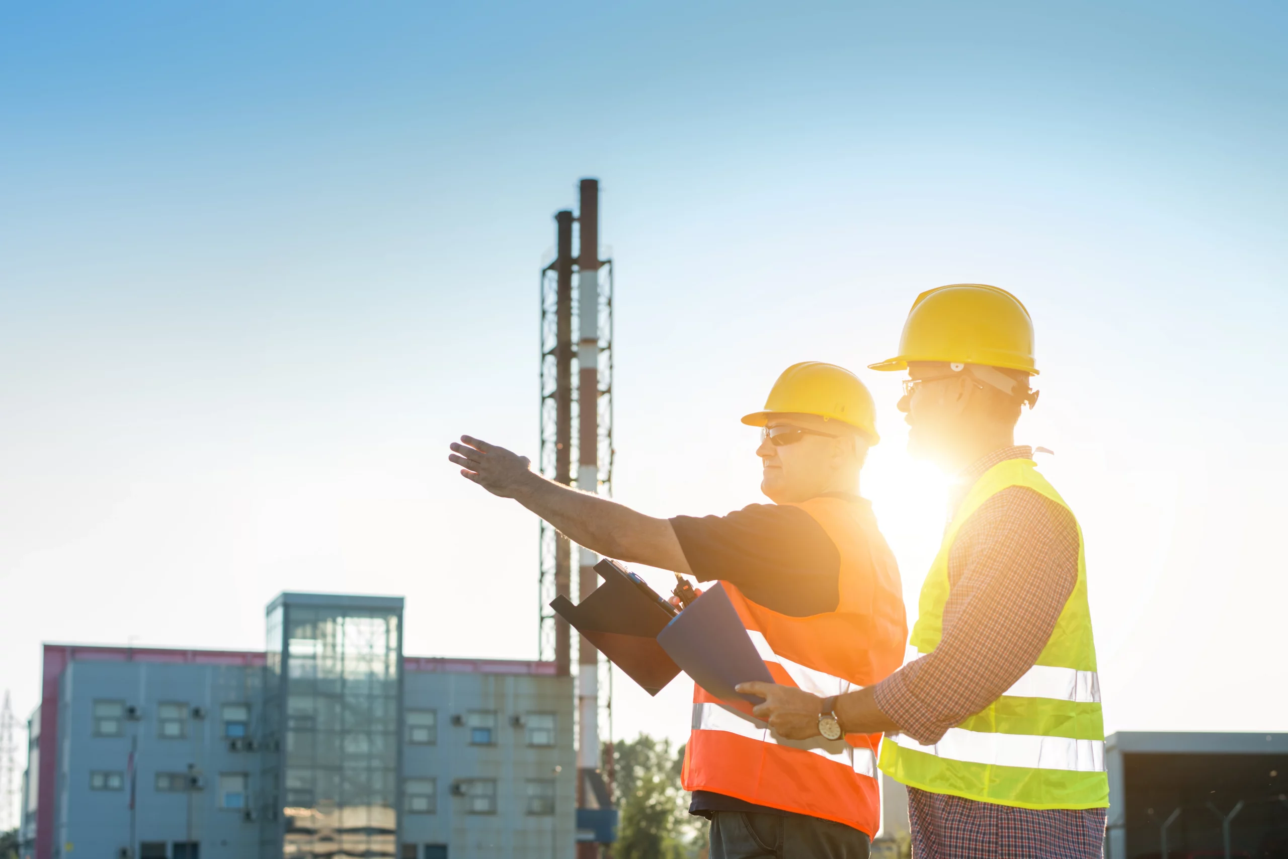 Zwei Ingenieure schauen in eine Richtung. Einer der beiden zeigt mit seinem Arm in diese Richtung