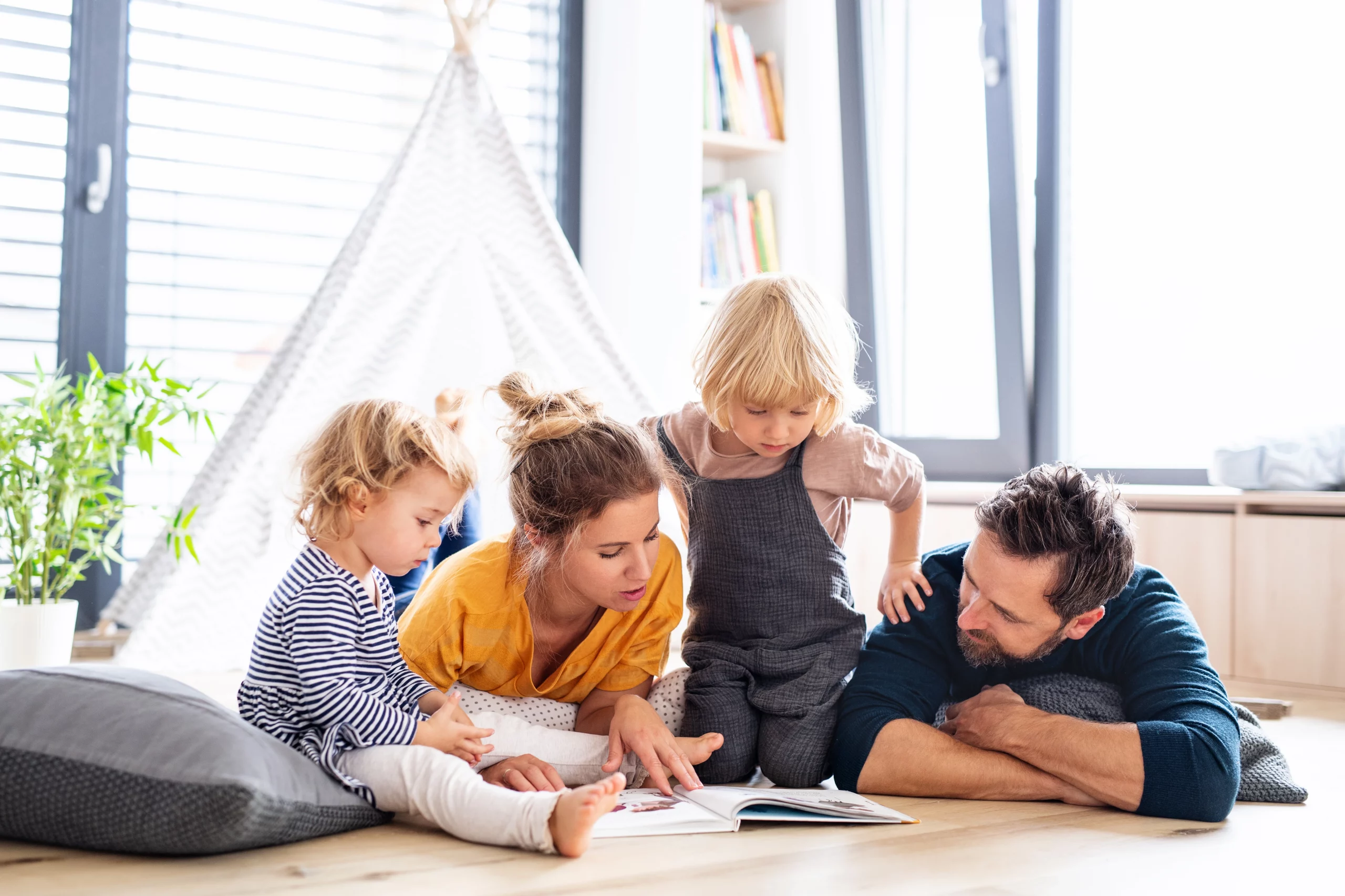 Familie liegt auf dem Boden und lesen gemeinsam ein Buch